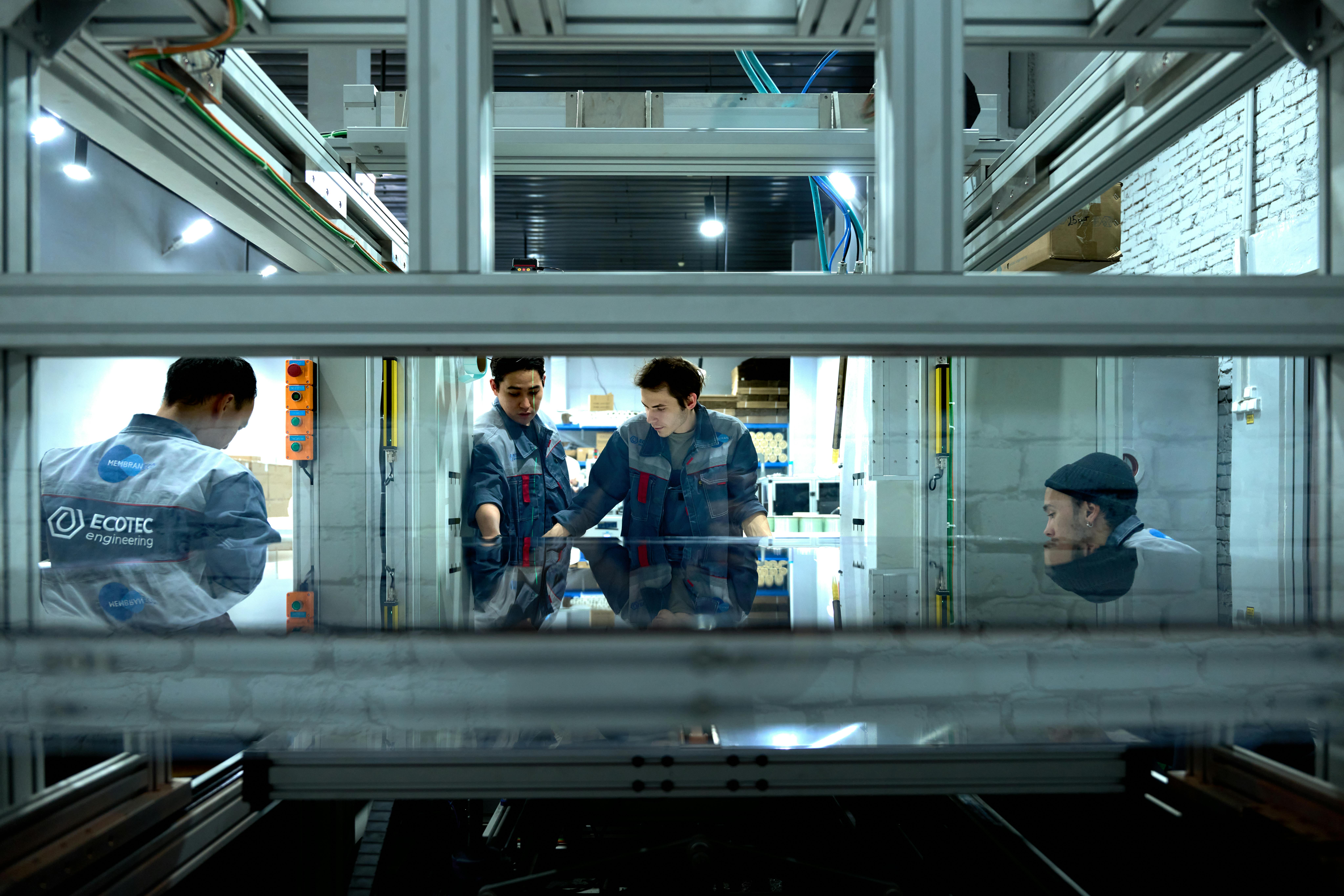 Engineers collaborate over advanced machinery in a high-tech indoor workspace.