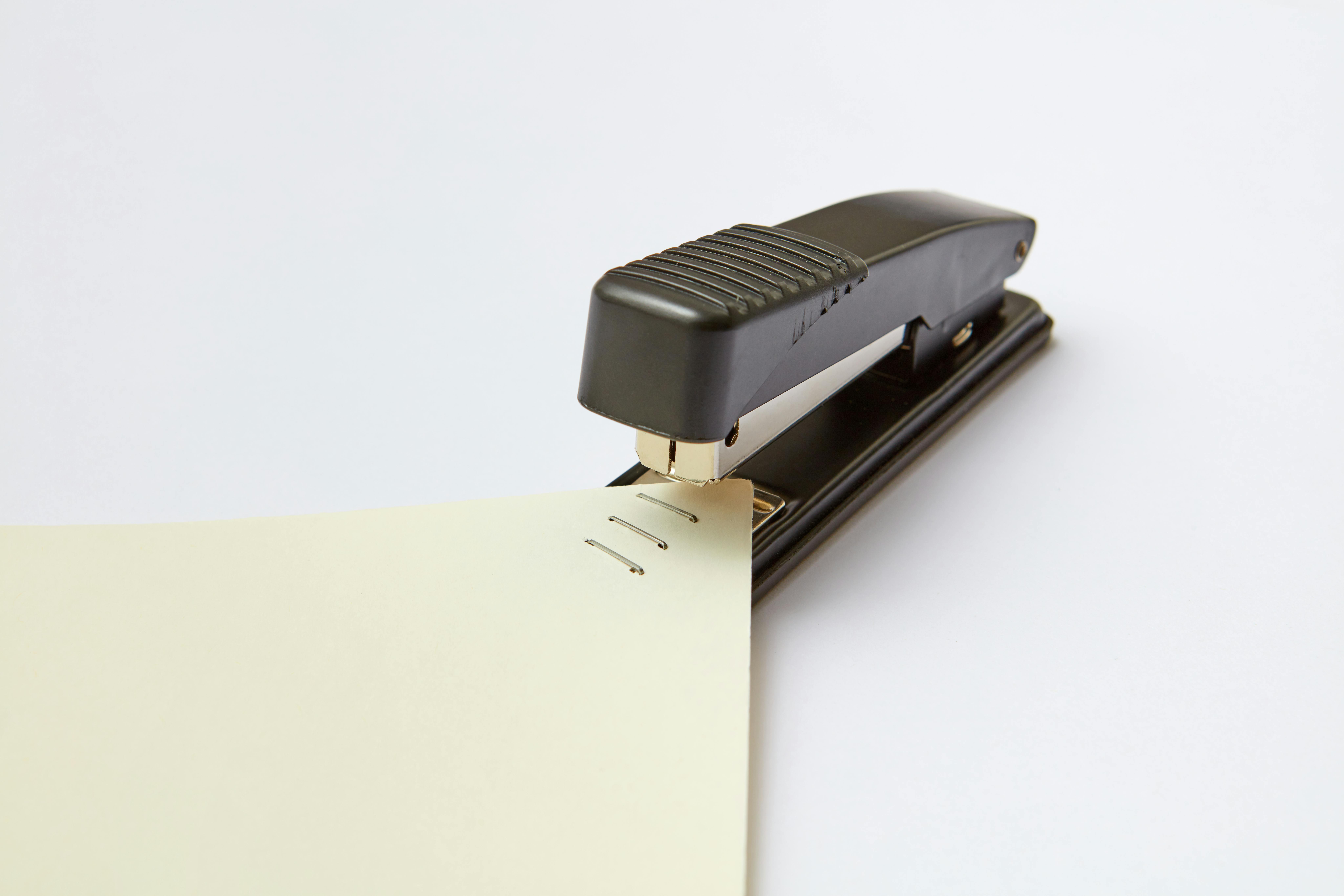 A close-up image of a black stapler fastening sheets of paper, ideal for office themes.